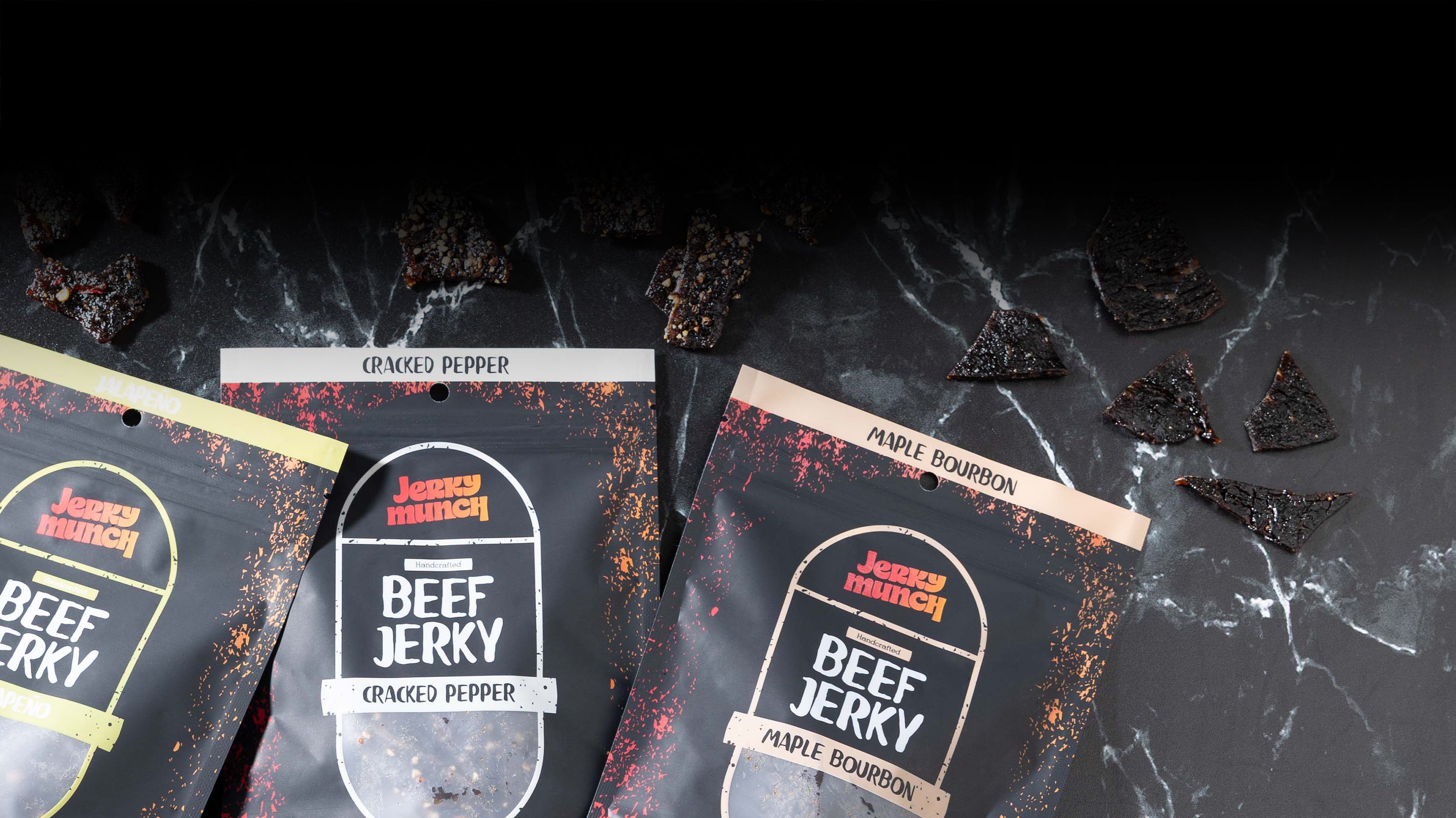 Three packages of Kosher Jerky Munch Beef Jerky on a dark surface with scattered jerky pieces.