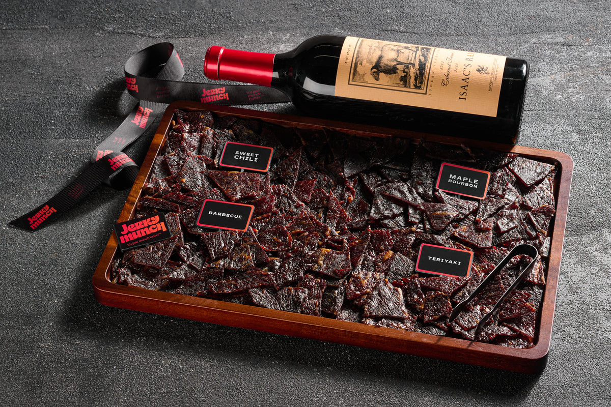 Kosher beef jerky board with flavor labels, served with a bottle of wine