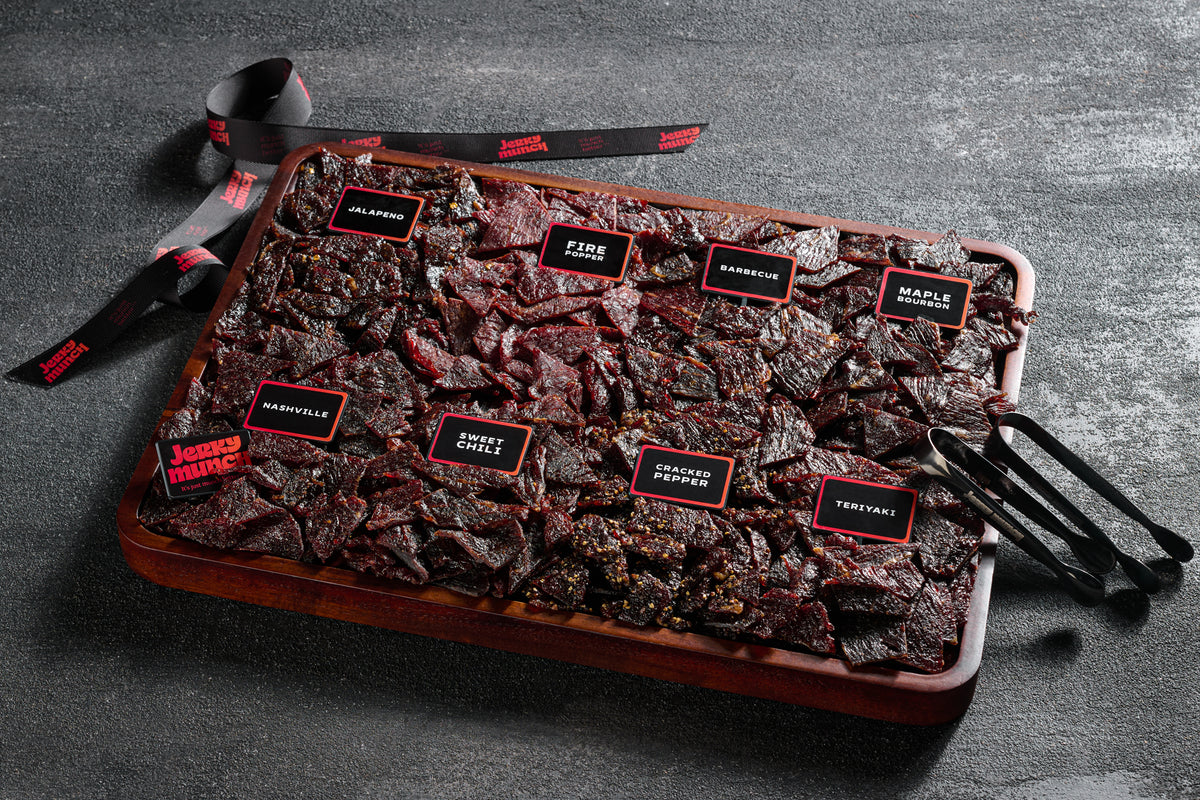 Jerky Munch kosher meat board with labeled beef jerky flavors on a wooden tray